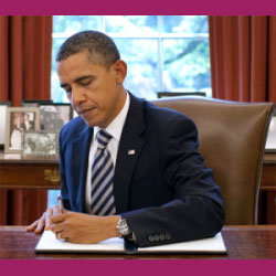 President Obama signs an executive order at his desk in the Oval Office