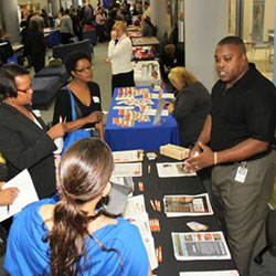 An employer at a job fair talks with potential new hires, some of whom may have disabilities.