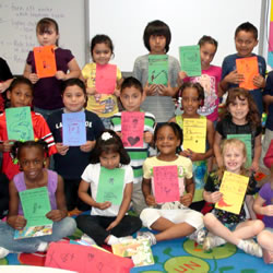 A class of young children holding up their first published books.